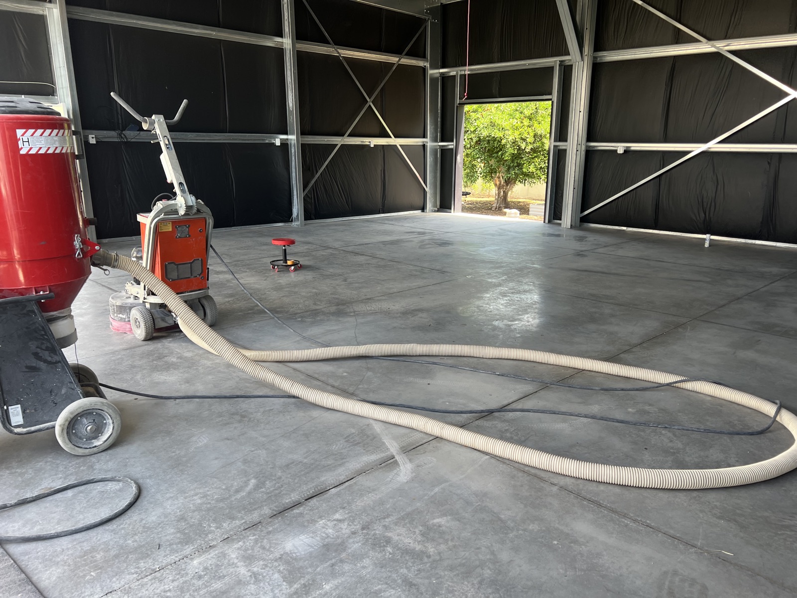 Diamond grinder with dust extraction preparing a concrete slab before coating