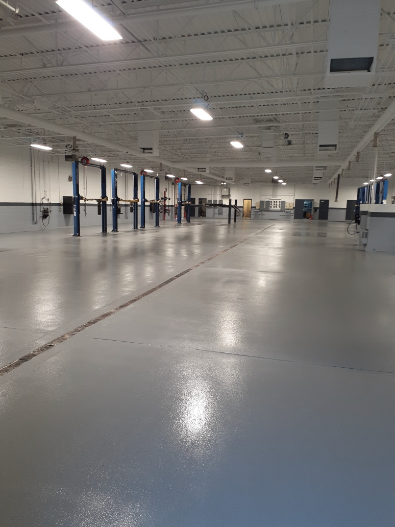 Freshly installed commercial epoxy flooring in a Phoenix automotive facility with two-post vehicle lifts