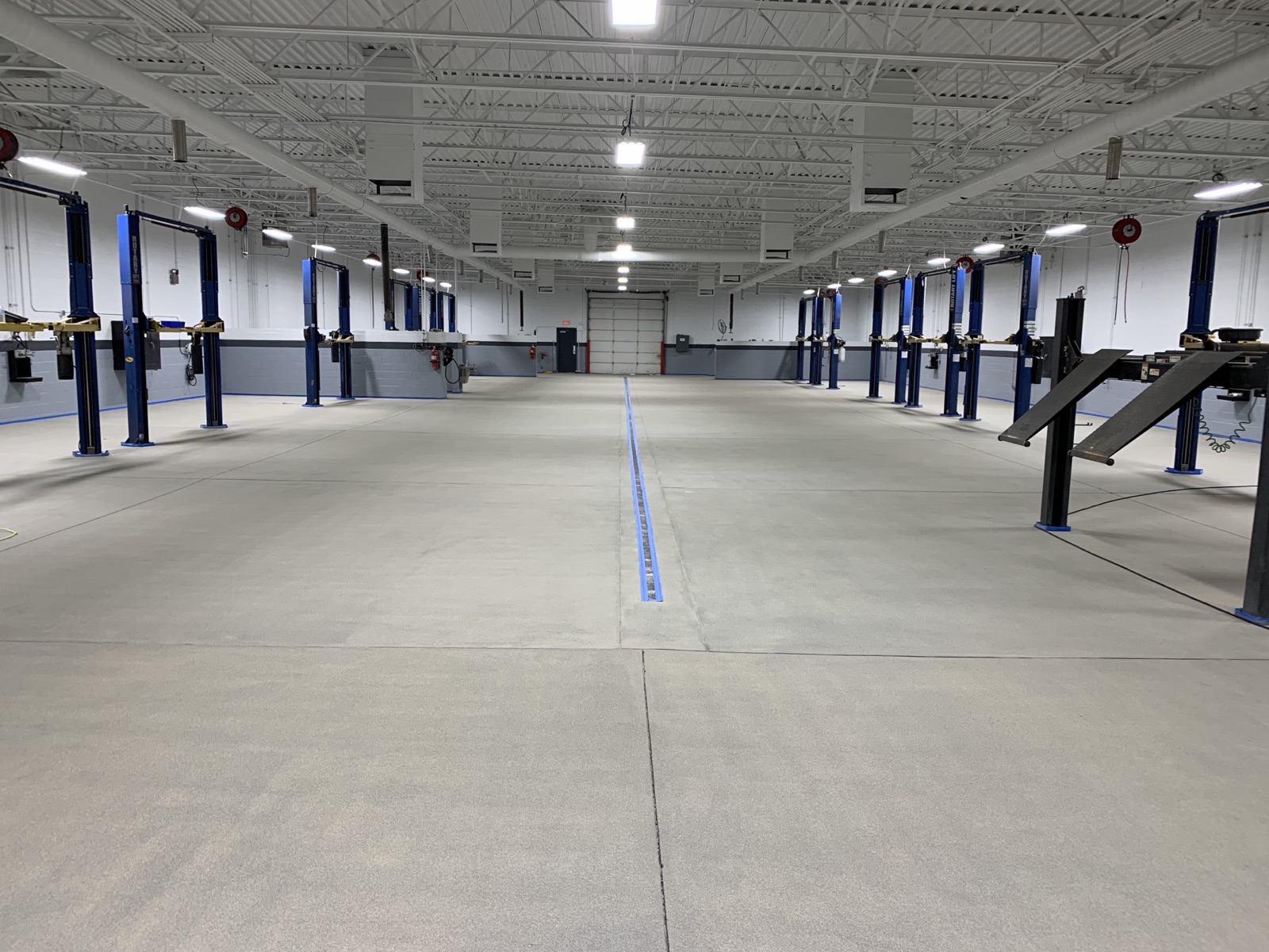 Finished commercial epoxy floor across the service bays of a Phoenix auto facility with two-post vehicle lifts