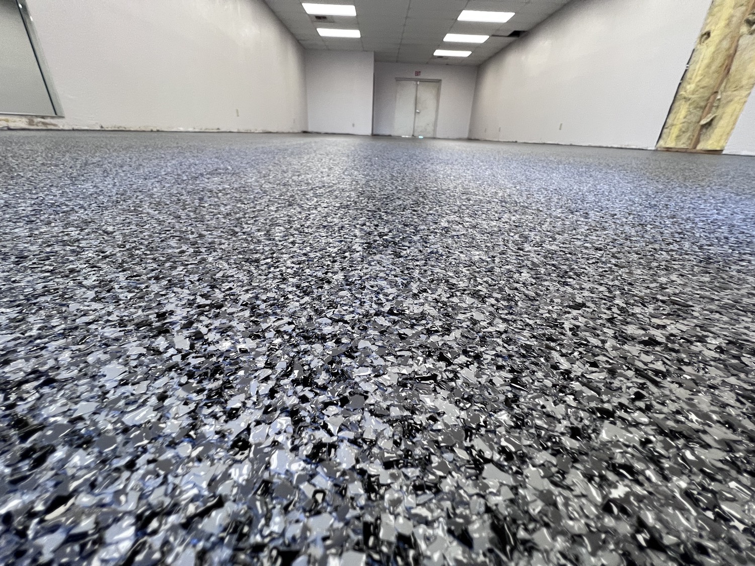 Low-angle close-up of a gray and black resinous flake epoxy floor in a Phoenix commercial space